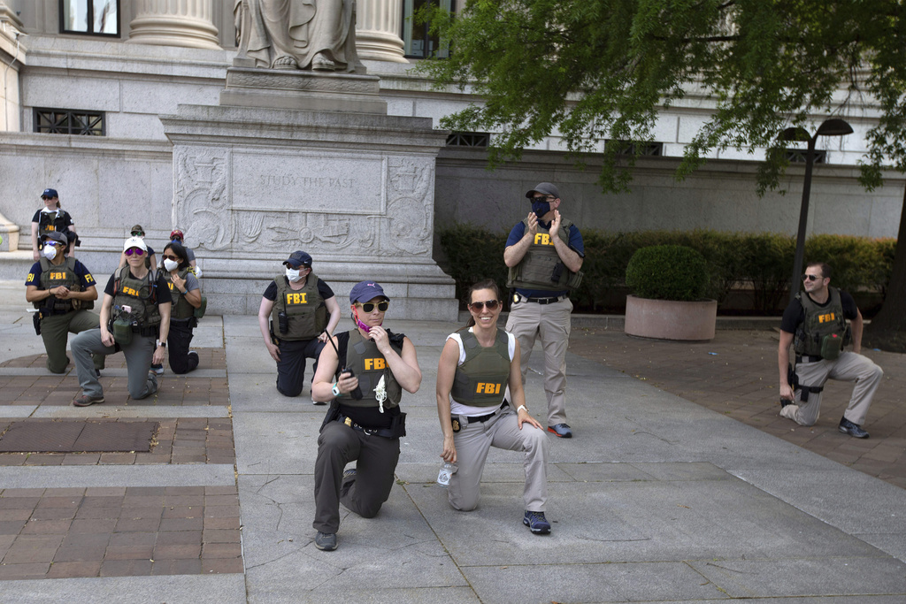 FILE - Federal Bureau of Investigation (FBI) officers take a knee with demonstrators, as they march on Pennsylvania Ave, June 4, 2020, in Washington, during a protest over the death of George Floyd, an unarmed black man, who died after a police officer kneeled on his neck for several minutes. (AP Photo/Jose Luis Magana, File)