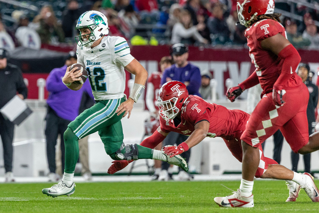 Tulane quarterback Jake Retzlaff (12) evades Temple linebacker Curly Ordonez, center, during the second half of an NCAA college football game, Saturday, Nov. 22, 2025, in Philadelphia. (AP Photo/Laurence Kesterson)