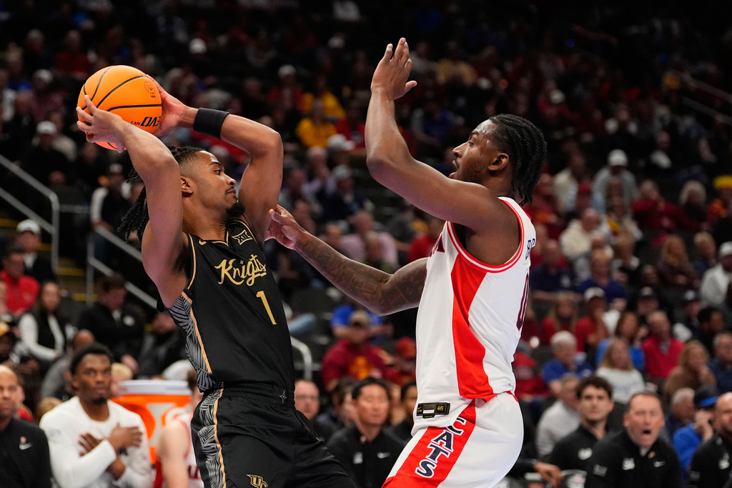 UCF's Themus Fulks, left, looks to pass around Arizona's Jaden Bradley during the first half of an NCAA college basketball game in the quarterfinal round of the Big 12 Conference tournament Thursday, March 12, 2026, in Kansas City, Mo. (AP Photo/Charlie Riedel)