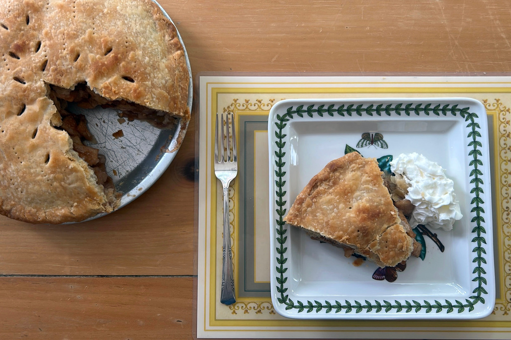 A freshly baked apple pie and a slice with whipped cream are dispayed in Marlborough, Massachusetts on June 26, 2026. (AP Photo/Bev Biller)