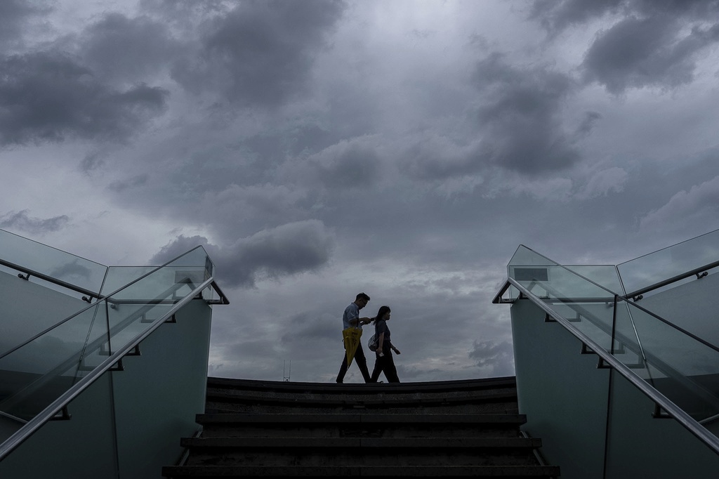 Pedestrians walk along the waterfront of Victoria Harbor ahead of Super Typhoon Ragasa approaches Hong Kong, Tuesday, Sept. 23, 2025. (AP Photo/Chan Long Hei)