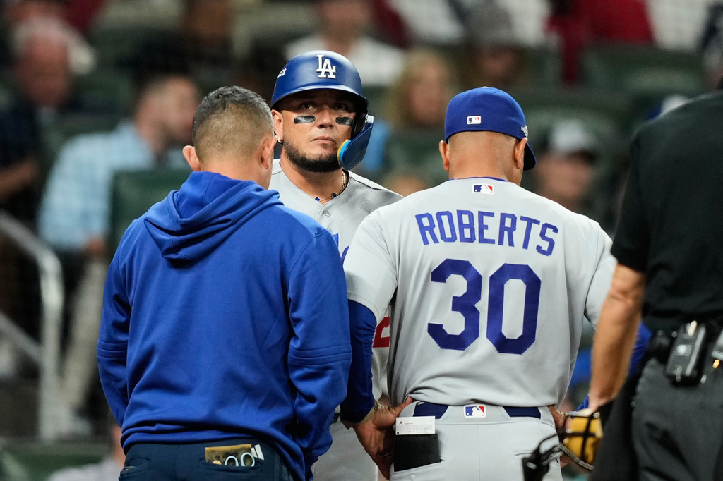 Los Angeles Dodgers' Miguel Rojas talks with manager Dave Roberts (30) and a member of the staff before leaving the game during the eighth inning in Game 3 of baseball's National League Division Series against the Atlanta Braves, Tuesday, Oct. 6, 2026, in Atlanta. (AP Photo/Brynn Anderson)