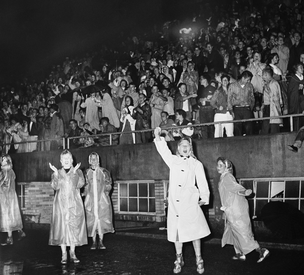 FILE - Central High School cheerleaders wearing raincoats lead a cheer during a game against Paducah, Ky., in a football game in Little Rock, Ark., on Sept. 19, 1958. (AP Photo/RWT, File)