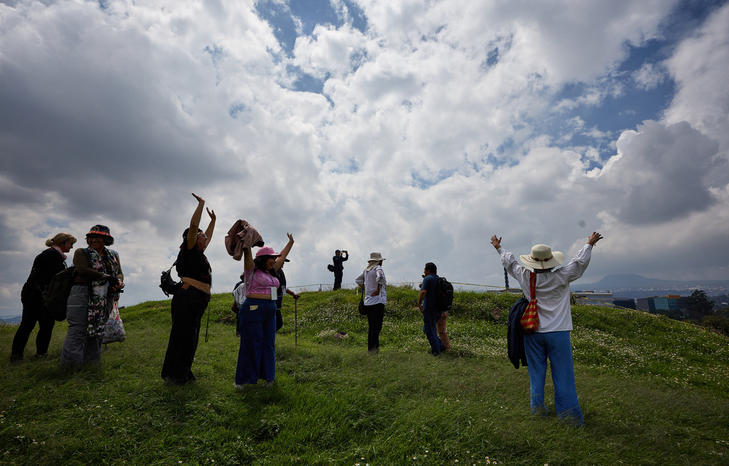 Tourists raise their arms at the Great Basement in the Cuicuilco Archaeological Zone during a tour organized by the National Institute of Anthropology and History in Mexico City, Sunday, Oct. 5, 2025. (AP Photo/Ginnette Riquelme)