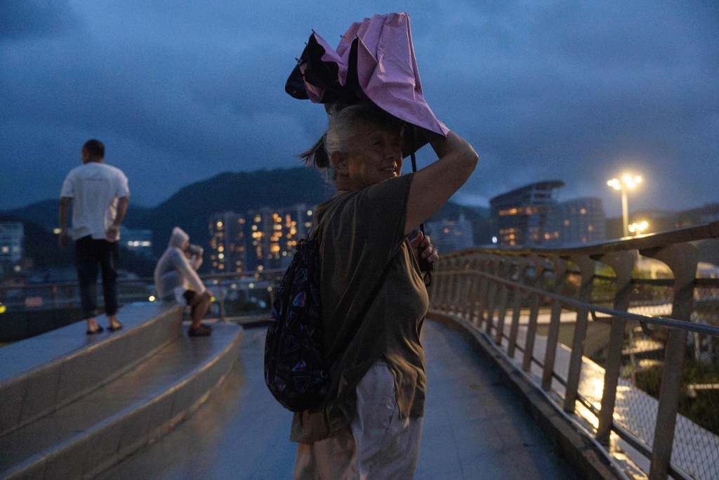 An elderly woman shelters from the rain in the aftermath of Super Typhoon Ragasa in Shenzhen in southern China's Guangdong province on Wednesday, Sept. 24, 2025. (AP Photo/Ng Han Guan)
