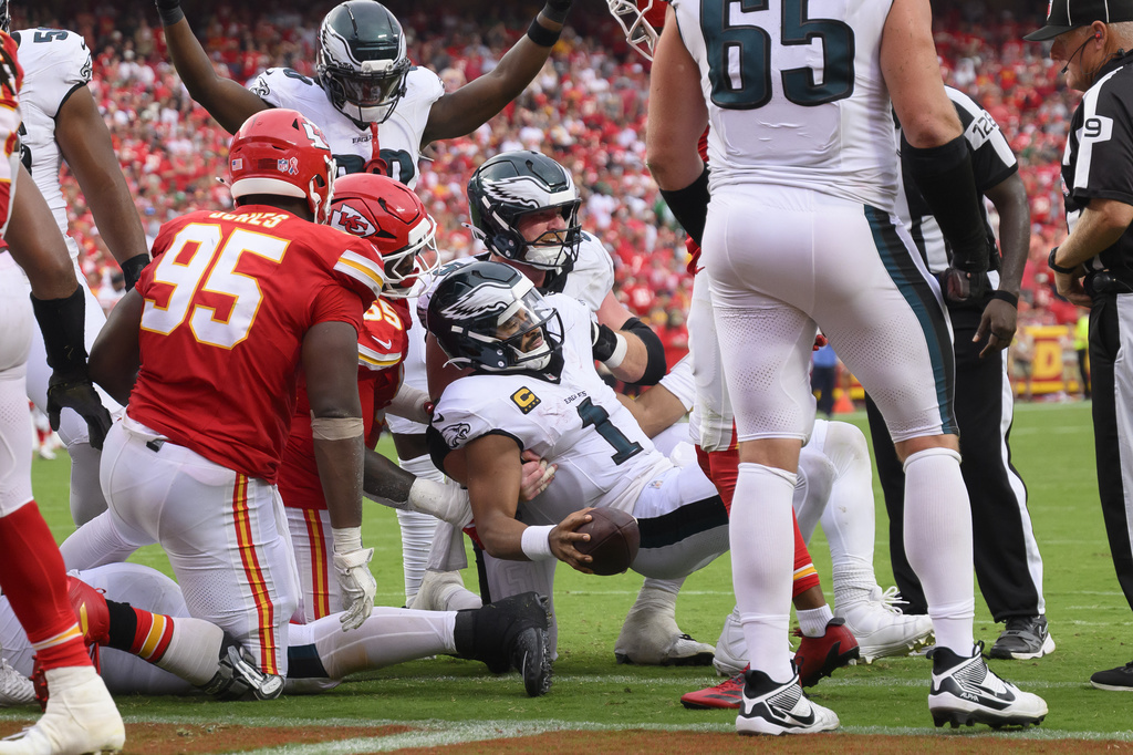 Philadelphia Eagles quarterback Jalen Hurts (1) is helped up by center Cam Jurgens, center back, after scoring a touchdown on a tush push late in the second half of an NFL football game against the Kansas City Chiefs, Sunday, Sept. 14, 2025, in Kansas City, Mo. (AP Photo/Reed Hoffmann)