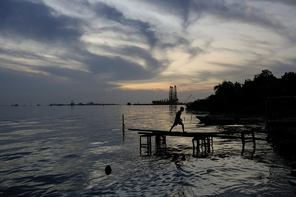 A boy walks on a jetty along the shore of Lake Maracaibo, near La Salina oil shipping terminal in Cabimas, Venezuela, June 18, 2025. (AP Photo/Matias Delacroix)