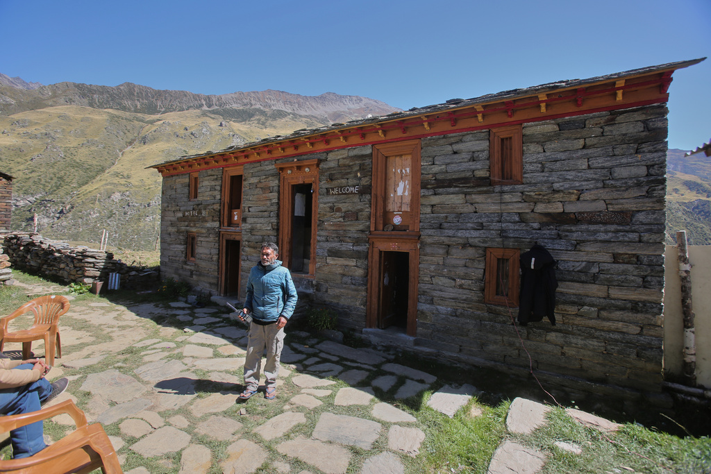 Raju Martolia holds a satellite phone outside his homestay in Martoli village in the northern Indian Himalayan state of Uttarakhand, on Oct. 4, 2025. (AP Photo/Satish Sharma)