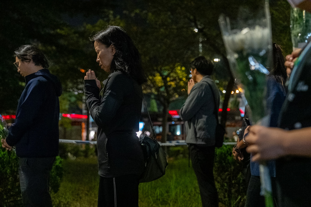 FILE - People offer flowers and pray for the victims near the site of Wednesday's fire at Wang Fuk Court, a residential estate in the Tai Po district of Hong Kong's New Territories, Sunday, Nov. 30, 2025. (AP Photo/Chan Long Hei, File)