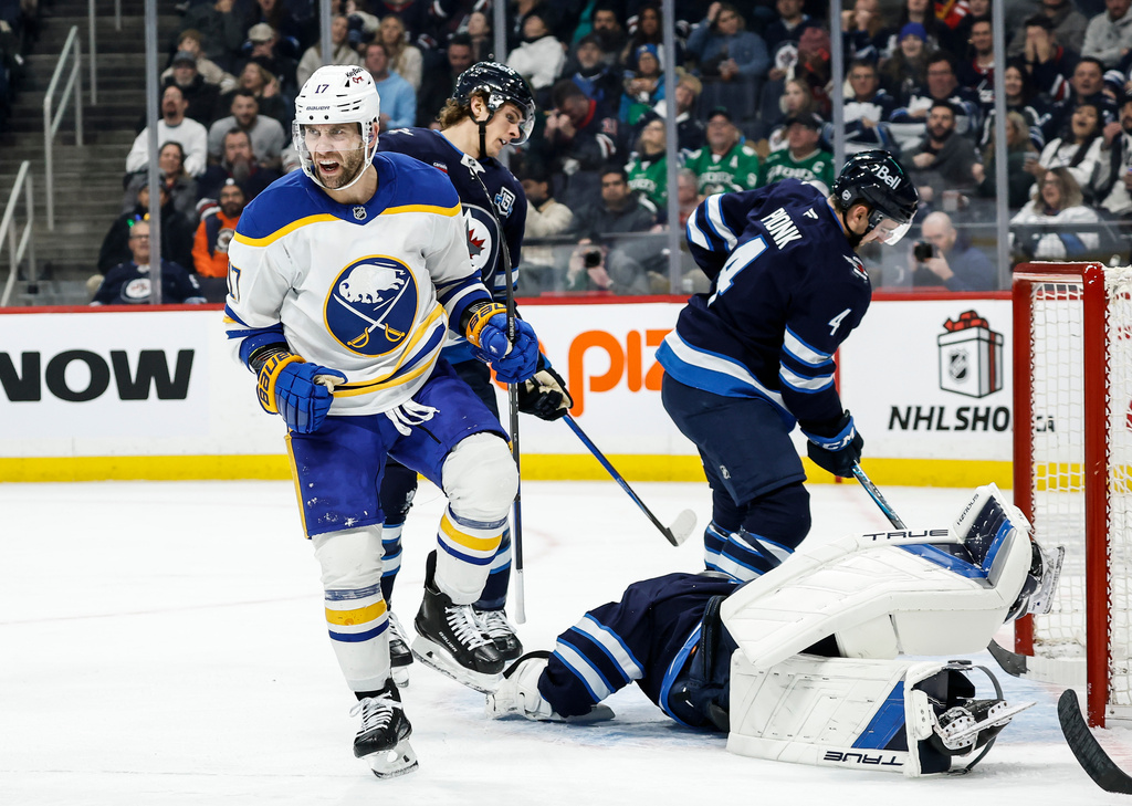 Buffalo Sabres' Jason Zucker (17) celebrates after his goal against Winnipeg Jets goaltender Eric Comrie, bottom right, during first-period NHL hockey game action in Winnipeg, Manitoba, Friday, Dec. 5, 2025. (John Woods/The Canadian Press via AP)