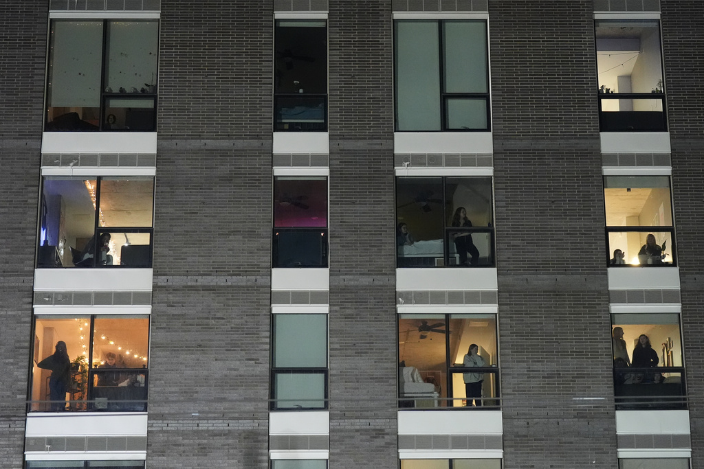 People watch from a building as police prepare to make arrests during a noise demonstration outside the Graduate by Hilton Minneapolis hotel on Wednesday, Jan. 28, 2026, in Minneapolis. (AP Photo/Adam Gray)