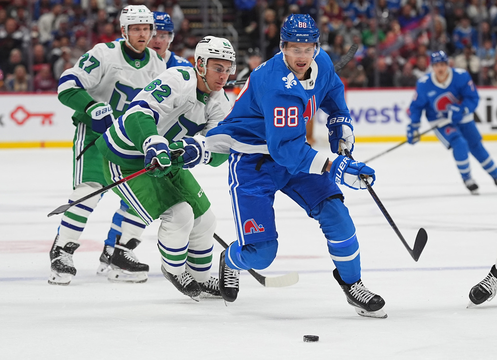 Colorado Avalanche center Martin Necas, front, drives past Carolina Hurricanes defenseman Charles Alexis Legault in the first period of an NHL hockey game Thursday, Oct. 23, 2025, in Denver. (AP Photo/David Zalubowski)
