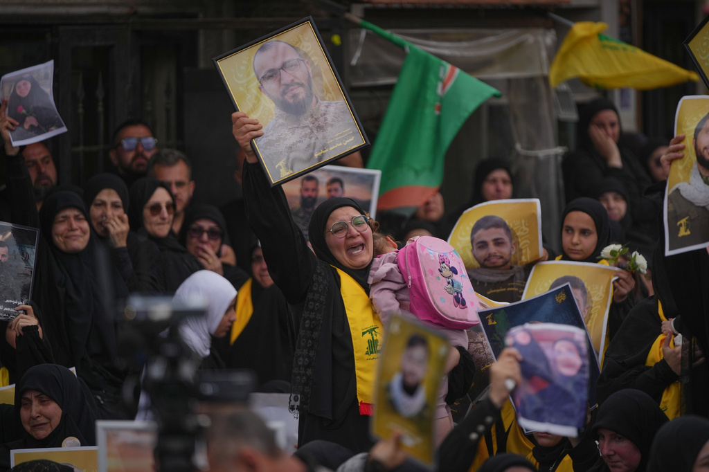 A woman mourns while holding a portrait of a Hezbollah fighter killed before the ceasefire in the war between Hezbollah and Israel during a mass funeral procession in the southern village of Kfar Sir, Lebanon, Tuesday, April 21, 2026. (AP Photo/Hassan Ammar)