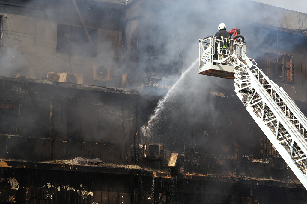 Firefighters pour water to control a massive fire that was broke out in a multi-story shopping mall overnight, in Karachi, Pakistan, Sunday, Jan. 18, 2026. (AP Photo/Mohammad Farooq)
