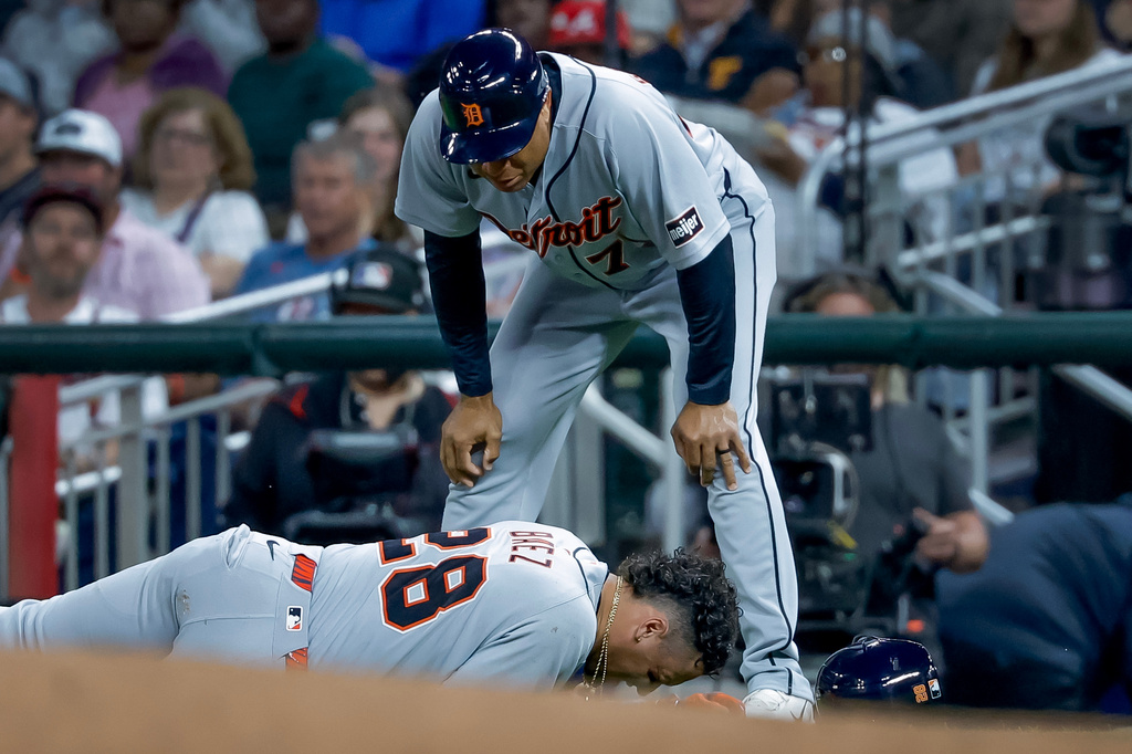Detroit Tigers' Javier Baez (28) reacts after injuring his right leg running to first base on a ground ball against the Atlanta Braves, as Detroit Tigers first base coach Anthony Sanders (77) looks on during the fifth inning of a baseball game, Tuesday, April 28, 2026, in Atlanta. (AP Photo/Erik S. Lesser)