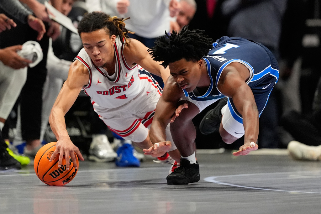 BYU's Robert Wright III, right, and Houston's Kingston Flemings dive after a loose ball during the first half of an NCAA college basketball game in the quarterfinal round of the Big 12 Conference tournament Thursday, March 12, 2026, in Kansas City, Mo. (AP Photo/Charlie Riedel)