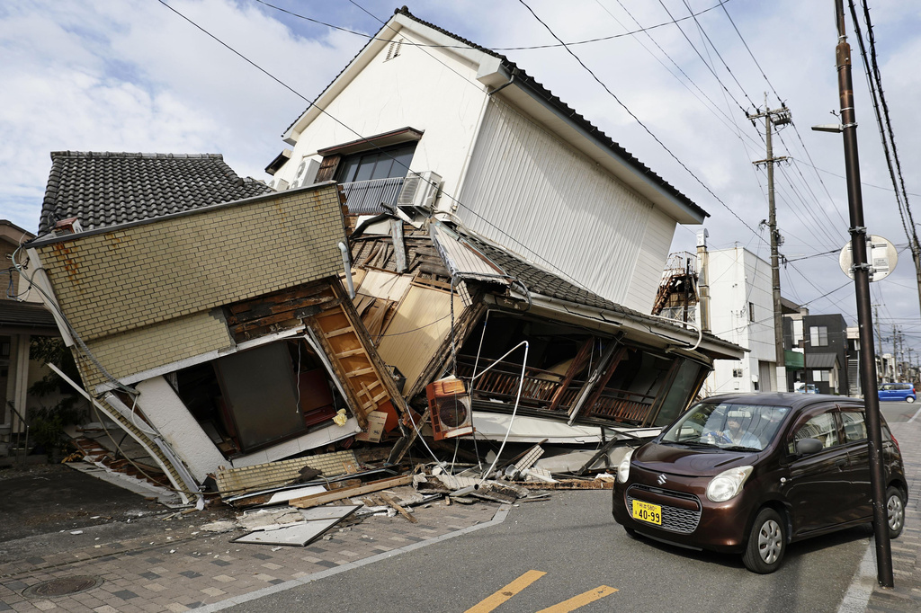 A vehicle passes by collapsed houses after an earthquake in Yatsushiro, Kumamoto prefecture, Wednesday, July 29, 2026.(Juntaro Yokoyama/Kyodo News via AP)