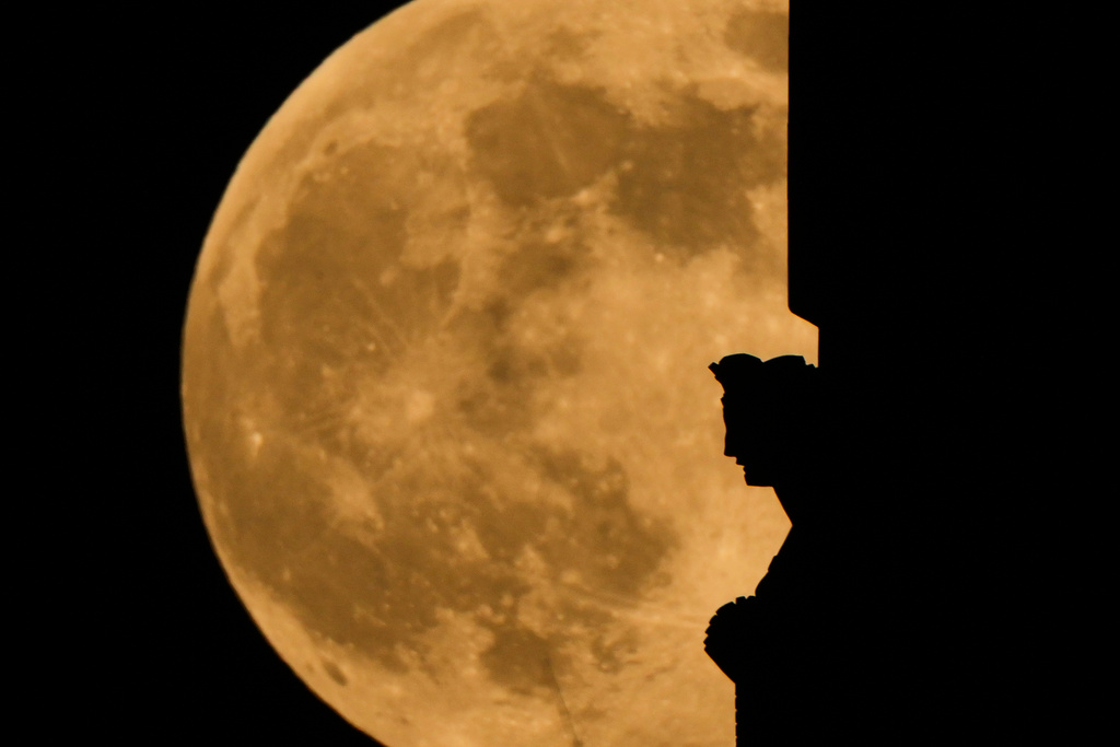 The full supermoon rises beyond a spirit statue atop the Liberty Memorial tower at the National World War Museum, Thursday, Dec. 4, 2025, in Kansas City, Mo. (AP Photo/Charlie Riedel)