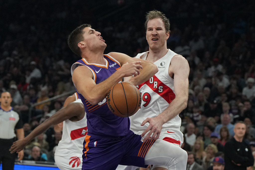 Toronto Raptors center Jakob Poeltl (19) knocks the ball away from Phoenix Suns guard Collin Gillespie during the first half of an NBA basketball game, Sunday, March 23, 2026, in Phoenix. (AP Photo/Rick Scuteri)