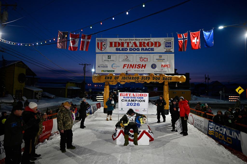 Jessie Holmes poses with his lead dogs Zeus, left, and Polar, after claiming his second straight Iditarod Trail Sled Dog Race championship, in Nome, Alaska, Tuesday March 17, 2026. (Marc Lester/Anchorage Daily News via AP)