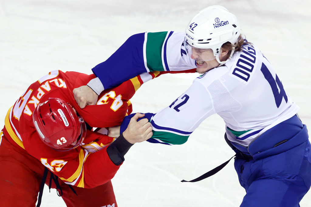 Vancouver Canucks' Curtis Douglas (42) fights Calgary Flames' Adam Klapka (43) during first-period NHL hockey game action in Calgary, Alberta, Saturday, March 28, 2026. (Larry MacDougal/The Canadian Press via AP)