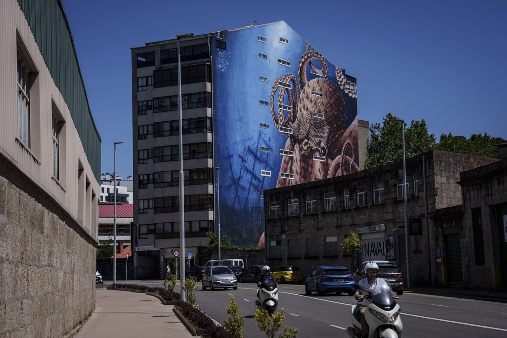 Vehicles move down a street with an octopus mural in the background Thursday, June 26, 2025, in Vigo, Spain. (AP Photo/Annika Hammerschlag)