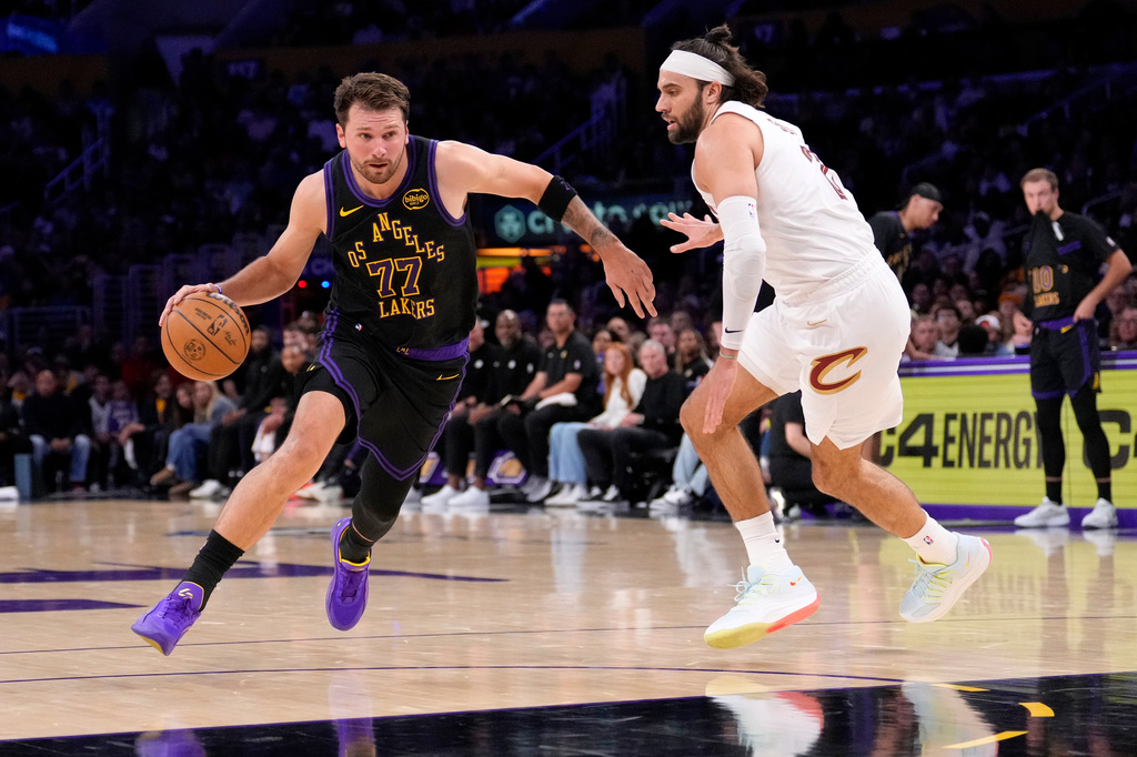 Los Angeles Lakers guard Luka Doncic, left, drives past Cleveland Cavaliers guard Max Strus during the first half of an NBA basketball game Tuesday, March 31, 2026, in Los Angeles. (AP Photo/Mark J. Terrill)