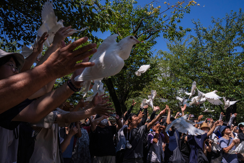 Visitors release doves at the Yasukuni Shrine on the 80th anniversary of Japan's surrender in World War II, in Tokyo, Friday, Aug. 15, 2025. (AP Photo/Louise Delmotte)