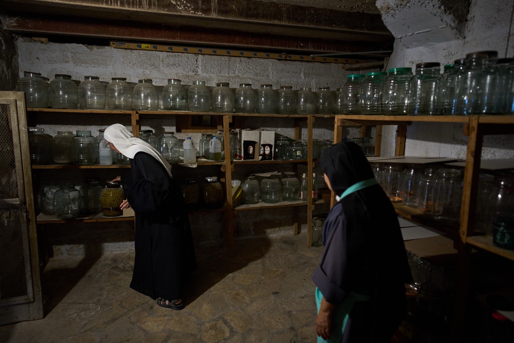 Sister Marie Benedicte, left, and Sister Colomba, two Catholic nuns, check on the olive preserves that were made in past years from the harvest in their monastery's garden on the Mount of Olives, in Jerusalem, Friday, Oct. 17, 2025. (AP Photo/Oded Balilty)