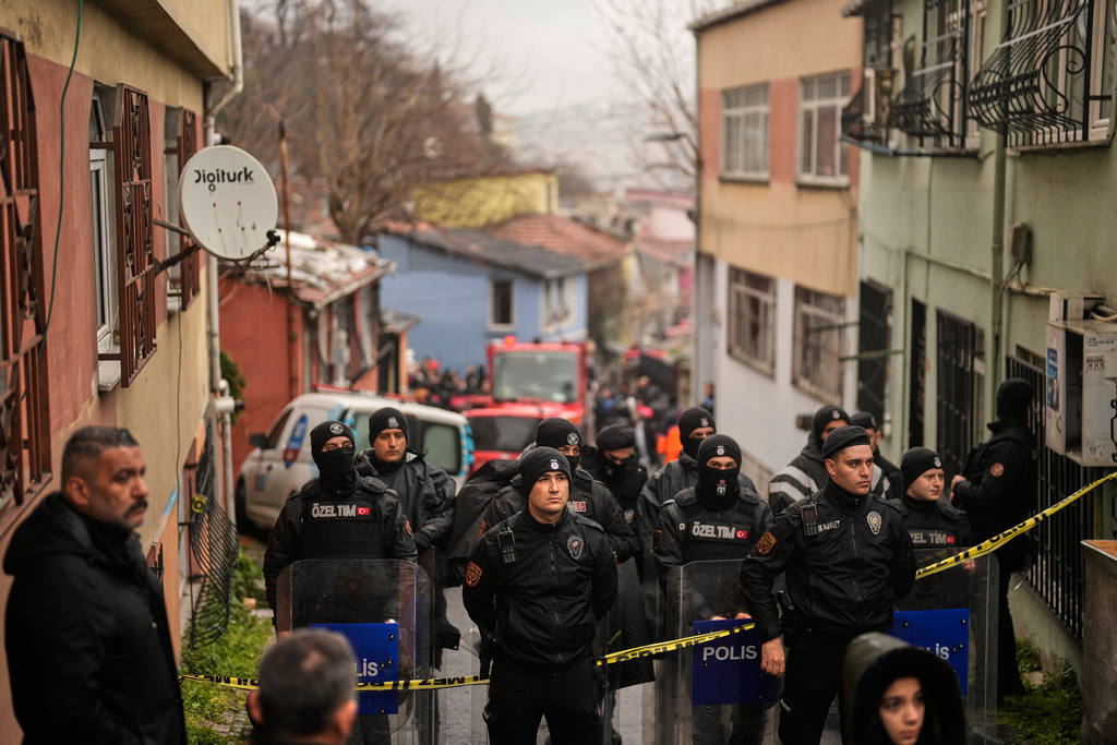Police secure the way to a site where two residential buildings collapsed in Istanbul, Sunday, March 22, 2026. (AP Photo/Khalil Hamra)