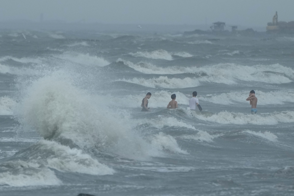 FILE - Men swim despite strong waves due to Typhoon Fung-wong along a coastal village on Nov. 10, 2025, in Navotas, Philippines. (AP Photo/Aaron Favila, File)