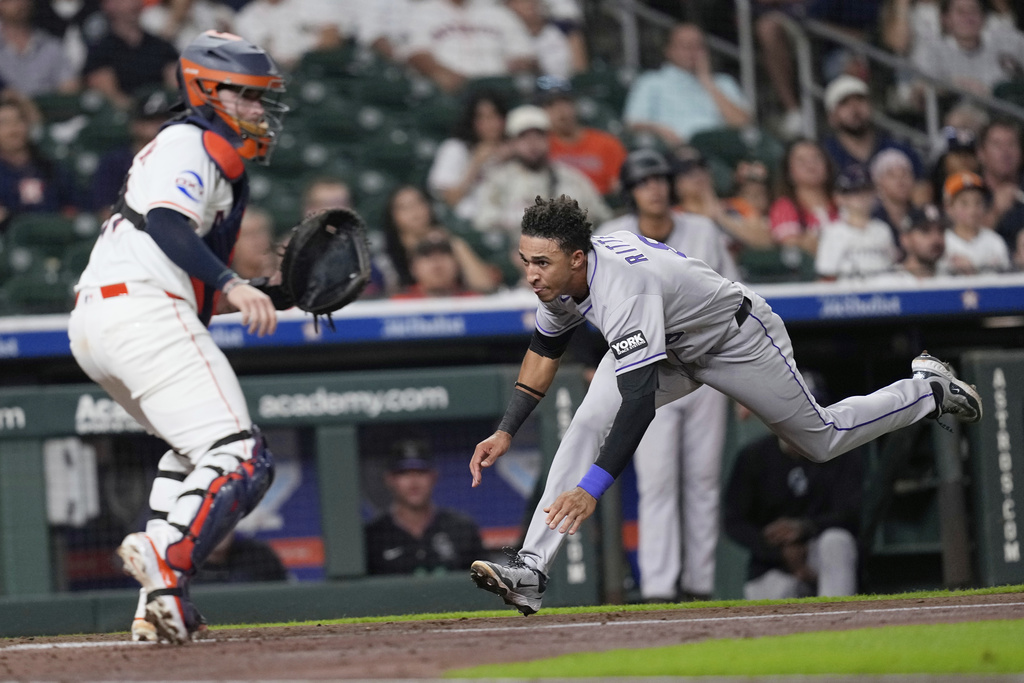 Colorado Rockies' Ryan Ritter, right, dives toward home plate to score as Houston Astros catcher Victor Caratini waits for the throw during the third inning of a baseball game Tuesday, Aug. 26, 2025, in Houston. (AP Photo/David J. Phillip)