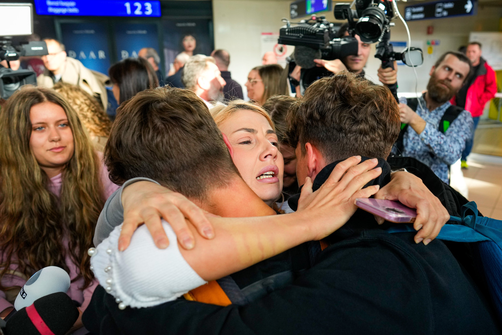 A family hugs after disembarking from an evacuation flight on a commercial airplane from Muscat, Oman, at the Henri Coanda International Airport in Otopeni, Romania, Friday, March 6, 2026. (AP Photo/Vadim Ghirda)
