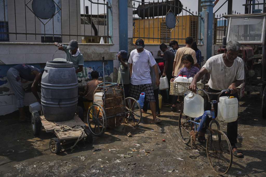 Palestinians collect drinking water at a desalination plant in Deir al-Balah, central Gaza Strip, Wednesday, Aug. 13, 2025. (AP Photo/Abdel Kareem Hana)