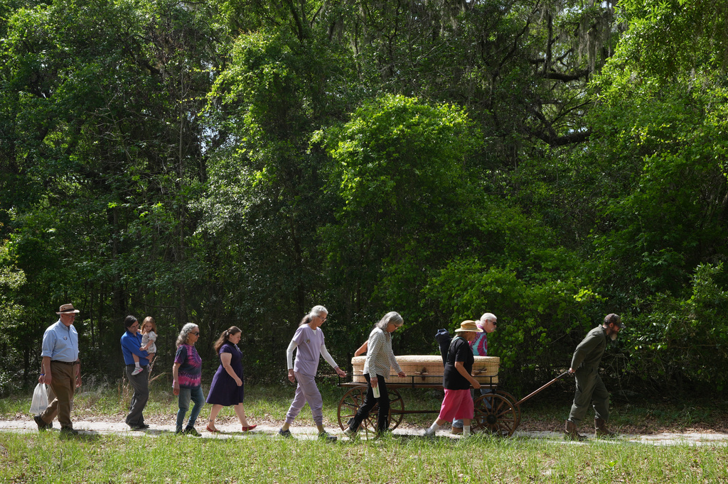 Friends and family of Jacqueline Betz push an Amish cart with her body at the Prairie Creek Conservation Center Cemetery, Monday, April 6, 2026, in Gainesville, Fla. (AP Photo/Marta Lavandier)
