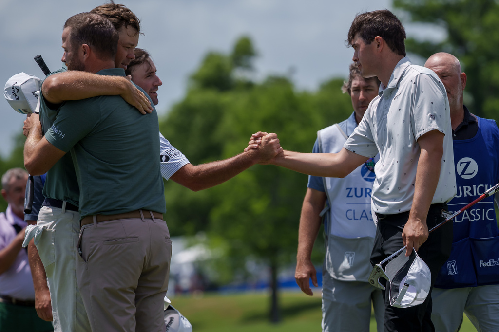 Austin Eckroat, background left, shakes hands with Davis Thompson reacts after missing a putt while Chris Kirk, first left, and Patton Kizzire embrace on the 18th hole during the first round of the PGA Zurich Classic golf tournament, Thursday, April 23, 2026, in Avondale, La. (AP Photo/Matthew Hinton)