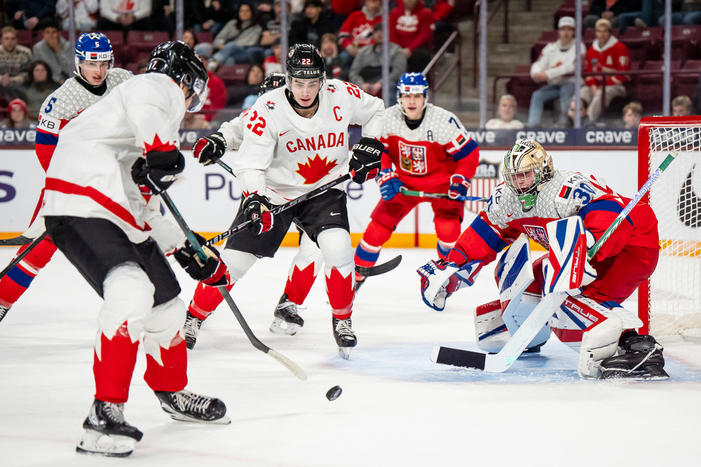 Canada's Michael Misa, front left, attacks Czechia goaltender Michal Orsulak (30) while Canada's Porter Martone (22) stands in front of the net during second-period IIHF World Junior Championship hockey game action in Minneapolis, Friday, Dec. 26, 2025. (Christopher Katsarov/The Canadian Press via AP)