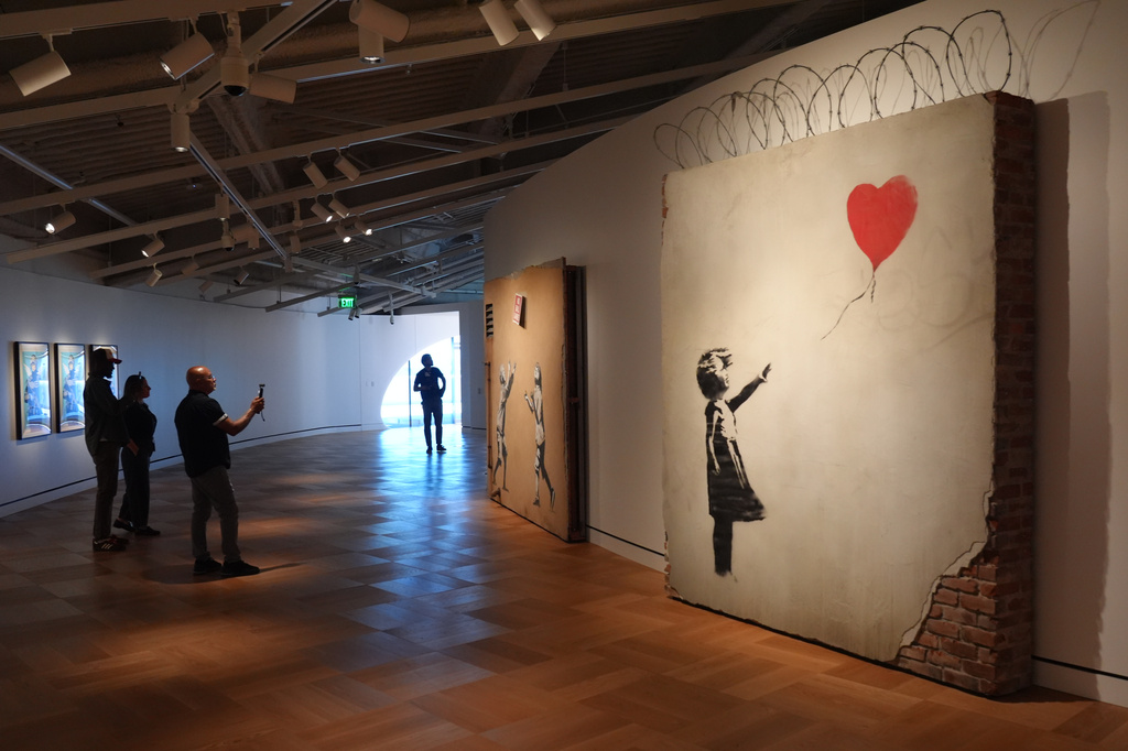 Visitors looks at artwork by the artist Banksy during a press preview for the Lucas Museum of Narrative Art on Wednesday, Sept. 2, 2026, in Los Angeles. (AP Photo/Chris Pizzello)
