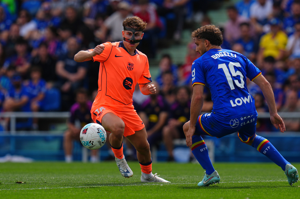 Barcelona's Fermin Lopez, left, and Getafe's Sebastian Boselli compete for the ball during the Spanish La Liga soccer match between Getafe and Barcelona in Getafe, Spain, Saturday, April 25, 2026. (AP Photo/Manu Fernandez)