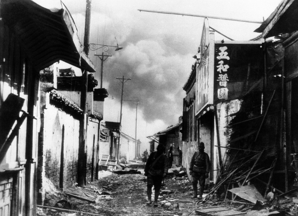 FILE - Chinese defenders fired buildings in Nanking as a last desperate resort to keep out the Japanese forces, but their efforts were in vain. Japanese troops in a shattered and deserted part of Nanking after forcing an entry. Flames in the background were just getting a hold on buildings which the Chinese fired, in December 1937. (AP Photo, File)