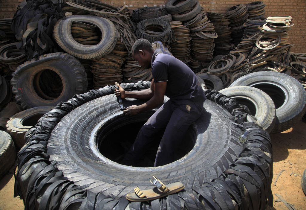 FILE - A Sudanese man cuts a heavy duty machine tire into rubber pieces at a shop in a market in Omdurman, Khartoum, Sudan, May 12, 2014. (AP Photo/Abd Raouf, File)