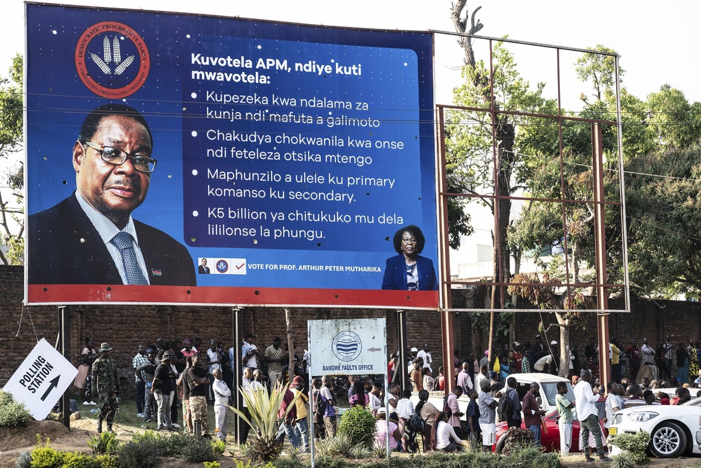 People line up to cast their votes under an election campaign billboard with a picture of presidential candidate Peter Mutharika, in Blantyre, Malawi, Tuesday, Sept. 16, 2025. (AP Photo/Thoko Chikondi)