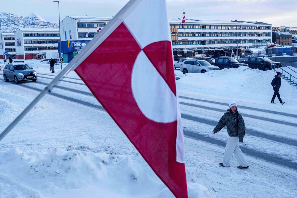 A woman walks on a street past a Greenlandic national flag in Nuuk, Greenland, Wednesday, Jan. 14, 2026. (AP Photo/Evgeniy Maloletka)