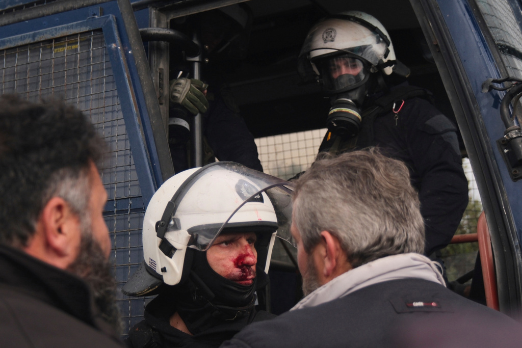 A injured police officer stands next to a police bus during clashes with officers blocking their march to Chania's airport on Crete, Greece, Monday, Dec. 8, 2025, amid protests over delayed EU farm subsidies. (AP Photo/Giannis Angelakis)