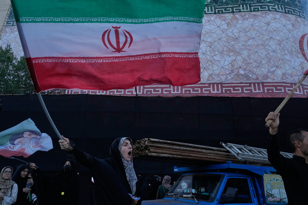 A woman waves an Iranian flags as she chants slogans against Iran and U.S. talks at the Islamic Revolution square in Tehran, Iran, Sunday, June 14, 2026. (AP Photo/Vahid Salemi)