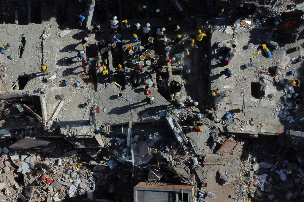 Volunteers and rescue workers use buckets to remove debris of a collapsed building a day after an earthquake struck Cali, Colombia, Tuesday, Aug. 11, 2026. (AP Photo/Santiago Saldarriaga)