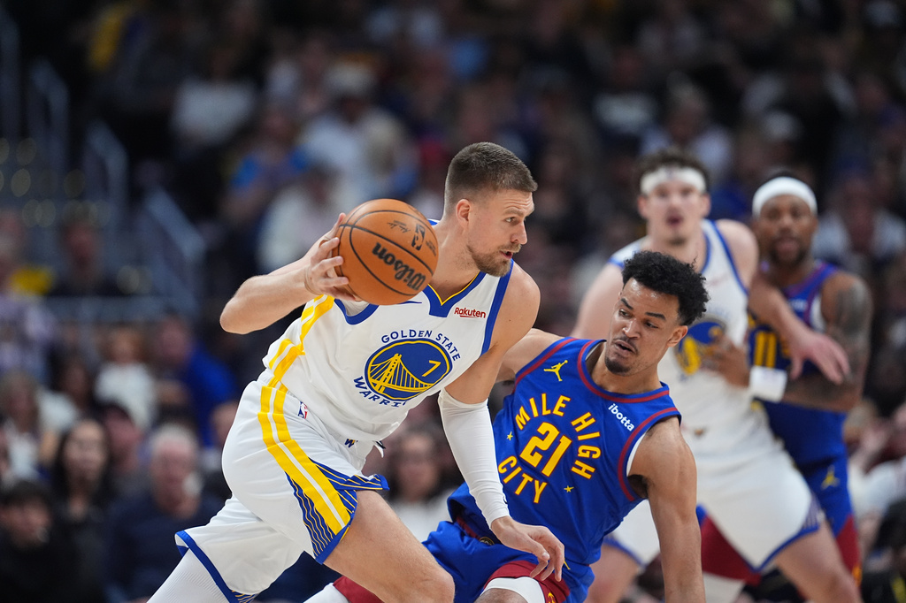 Golden State Warriors forward Kristaps Porziņģis, left, drives past Denver Nuggets forward Spencer Jones in the first half of an NBA basketball game Sunday, March 29, 2026, in Denver. (AP Photo/David Zalubowski)