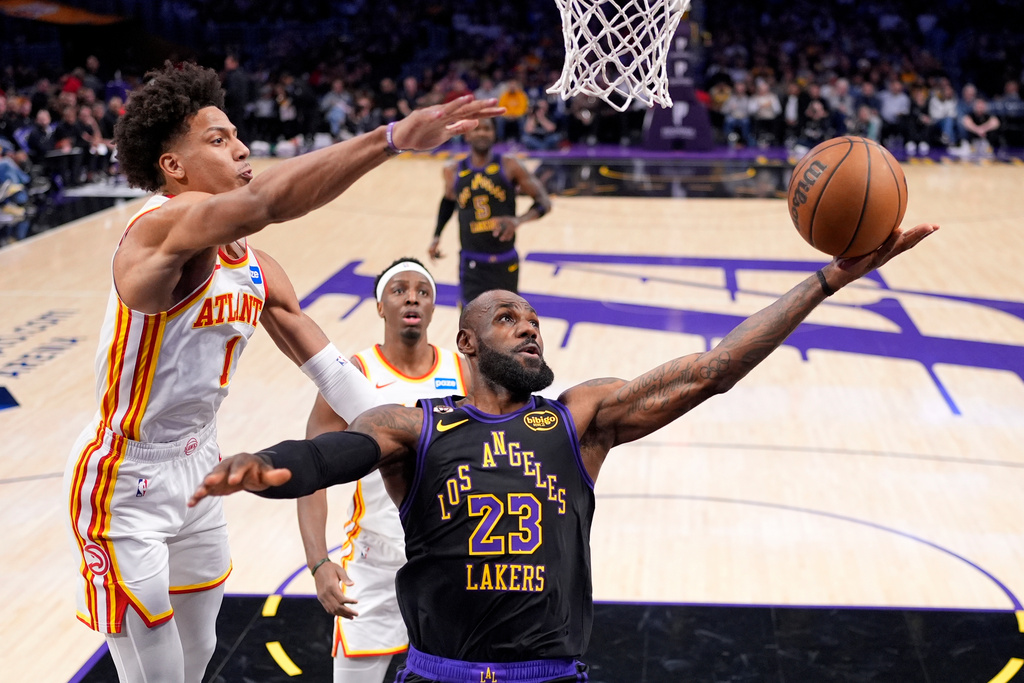 Los Angeles Lakers forward LeBron James, right, shoots as Atlanta Hawks forward Jalen Johnson, left, defends during the first half of an NBA basketball game Tuesday, Jan. 13, 2026, in Los Angeles. (AP Photo/Mark J. Terrill)