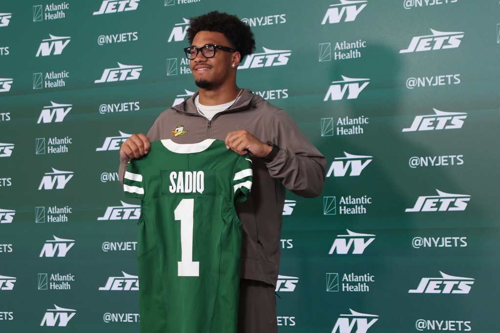 New York Jets first round draft pick Kenyon Sadiq holds up his jersey during an introductory press conference at the NFL team's training facility, Saturday, April 25, 2026, in Florham Park, N.J. (AP Photo/Heather Khalifa)