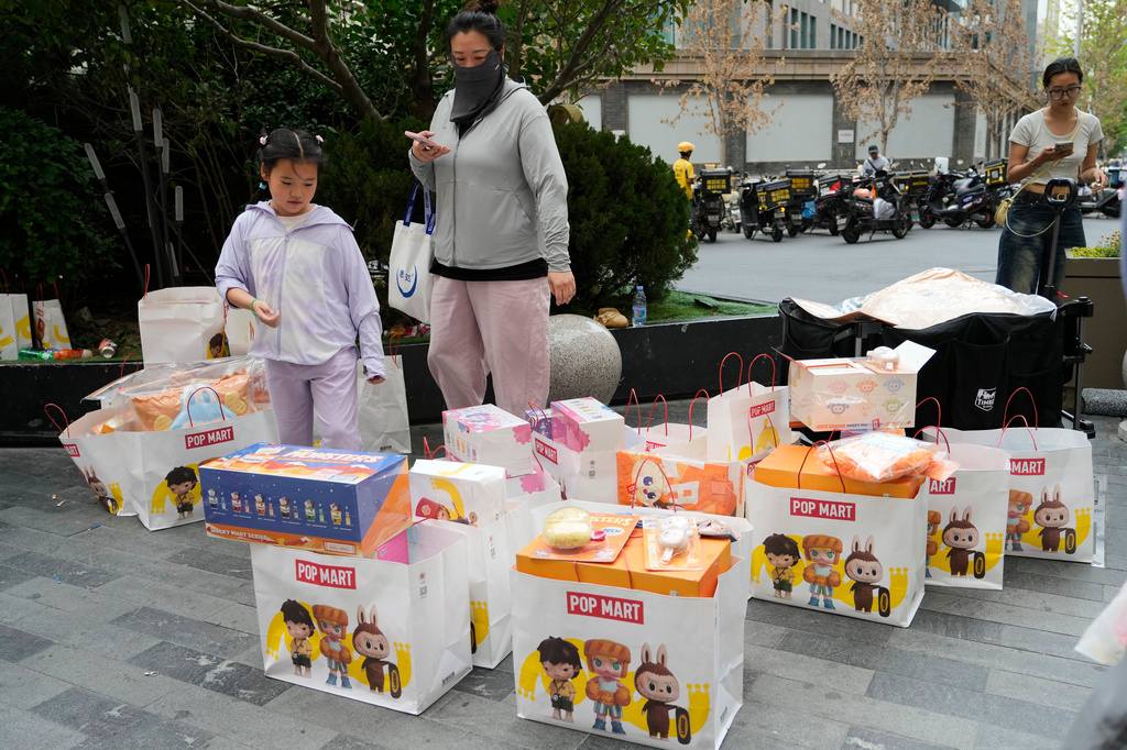 Shoppers pass by bags of Labubu merchandise from PopMart outside a mall, in Beijing, Friday, June 13, 2025. (AP Photo/Ng Han Guan)